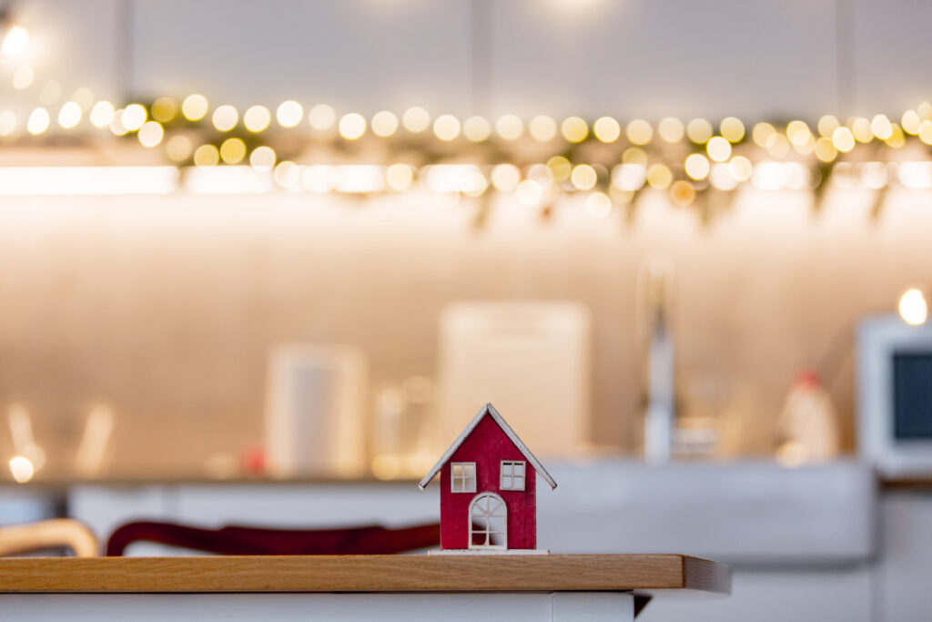 house on a table in a kitchen with Christmas lights